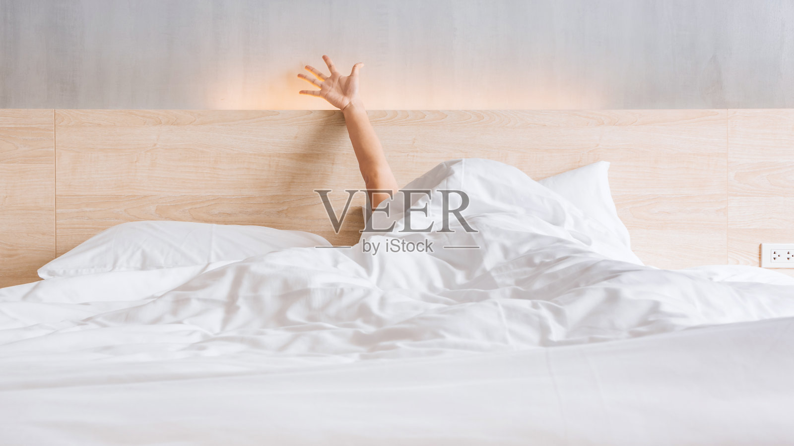 清晨，男人醒来后，在床上伸着他的胳膊照片摄影图片