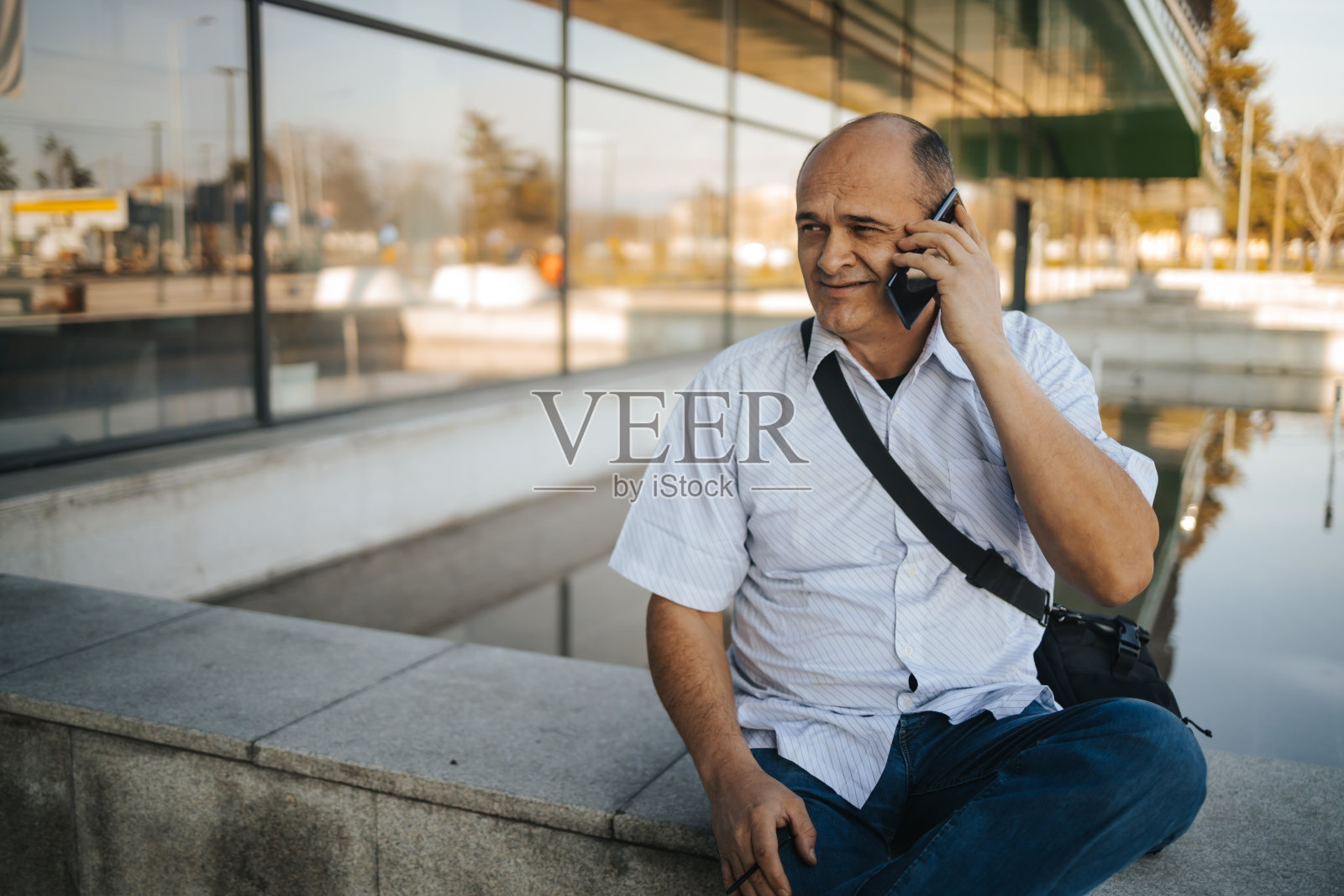 一个成熟的商人在办公大楼前打电话照片摄影图片