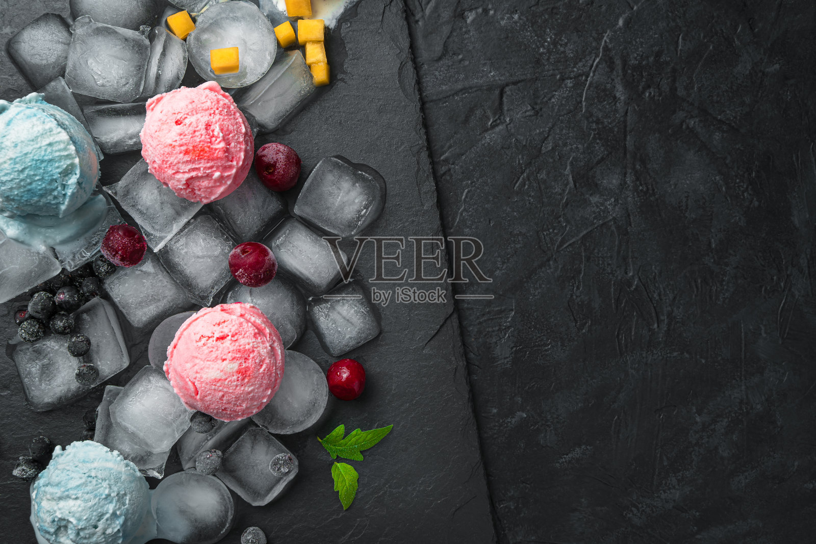 黑色的桌子上放着几块冰上的浆果冰淇淋球。顶视图,特写照片摄影图片