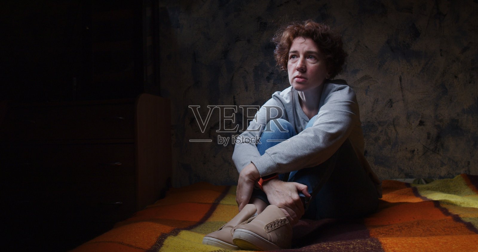 沮丧的女人在黑暗的房间里一动不动地坐在沙发上照片摄影图片