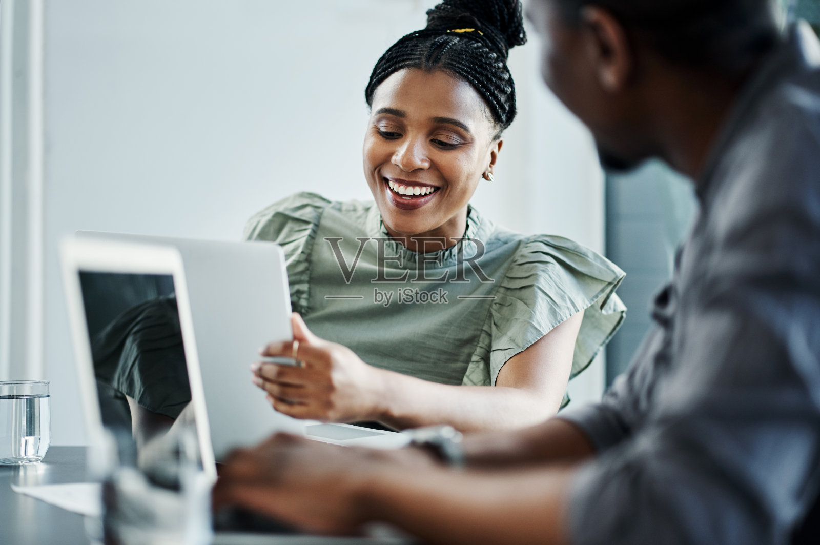 两个年轻的商人一起坐在办公室里，一边使用科技一边讨论照片摄影图片