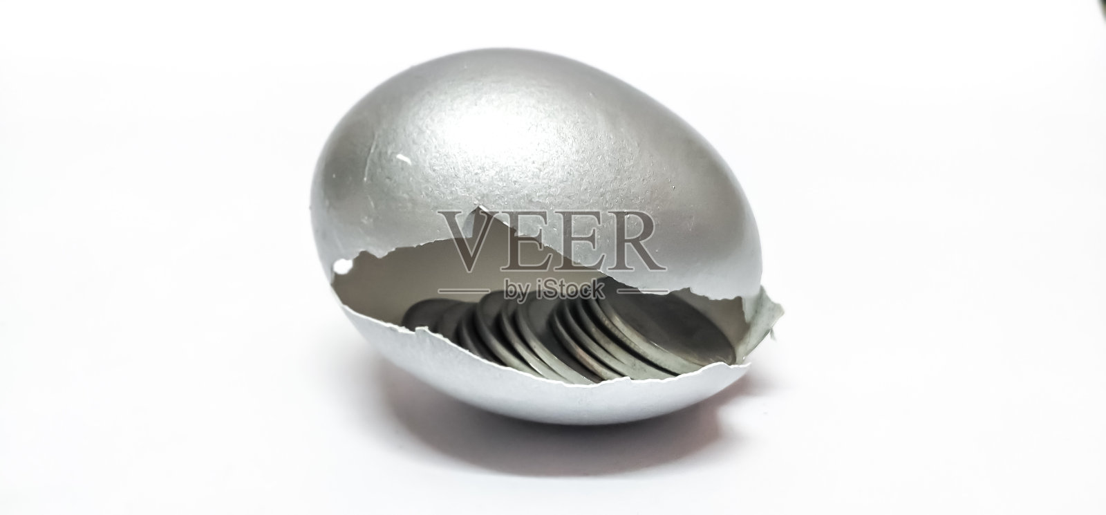 特写破碎的银蛋壳与硬币孤立在一个白色的背景。照片摄影图片