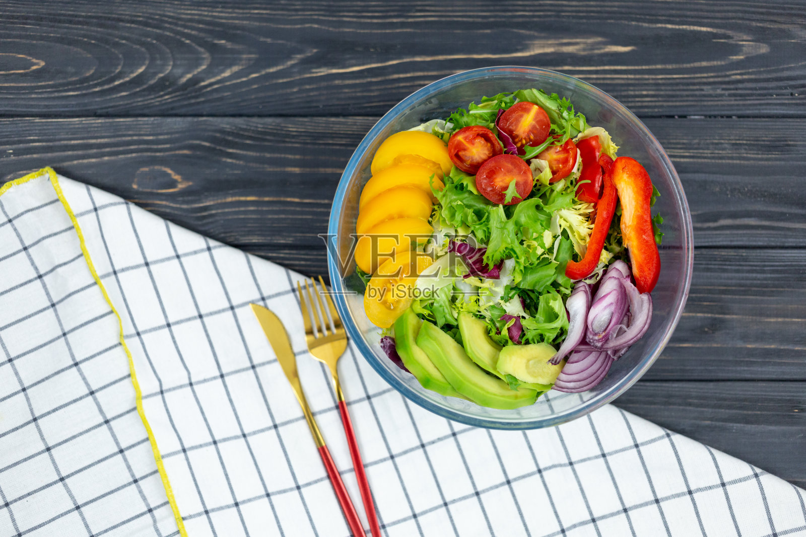 新鲜的绿色沙拉，牛油果，番茄，胡椒，洋葱放在一个白色的大碗里，放在木托盘上。素食沙拉与绿色混合叶子和蔬菜。灰色表上的顶视图。健康的素食。近距离照片摄影图片