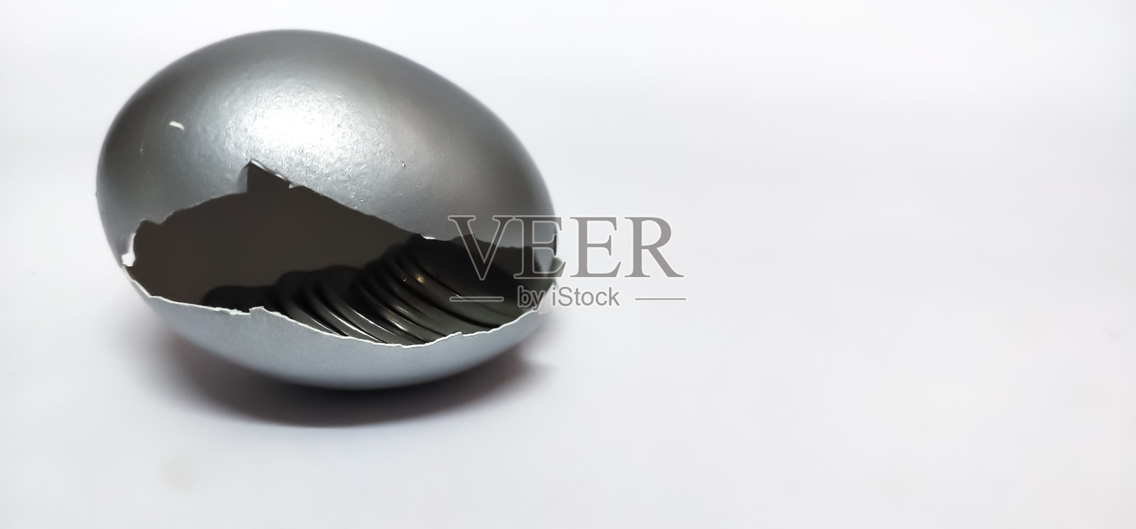 特写破碎的银蛋壳与硬币孤立在一个白色的背景。照片摄影图片