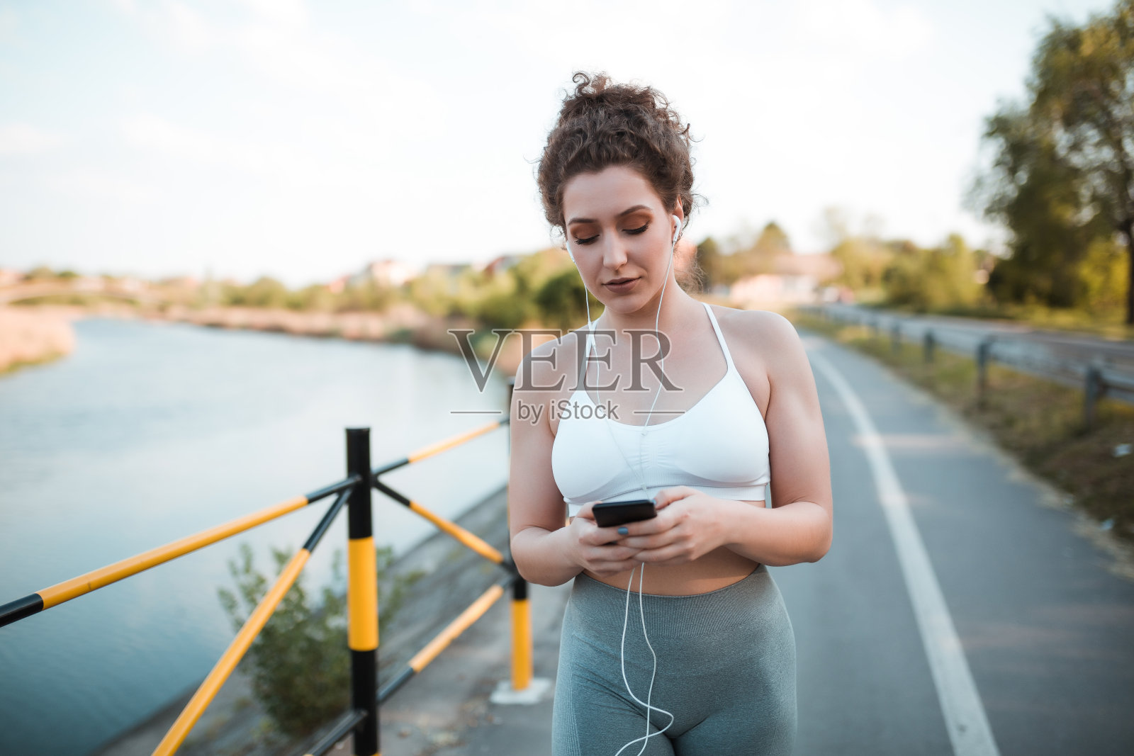 迷人的年轻女孩穿着运动服听她最喜欢的音乐，同时在训练后给某人发短信照片摄影图片