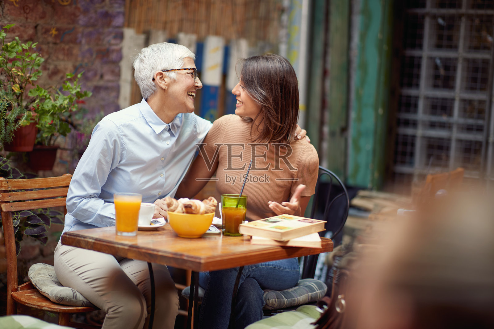 一个年长的女人有一个很好的时间在一个友好的谈话在酒吧与她的年轻女性朋友。休闲，酒吧，友谊，户外照片摄影图片