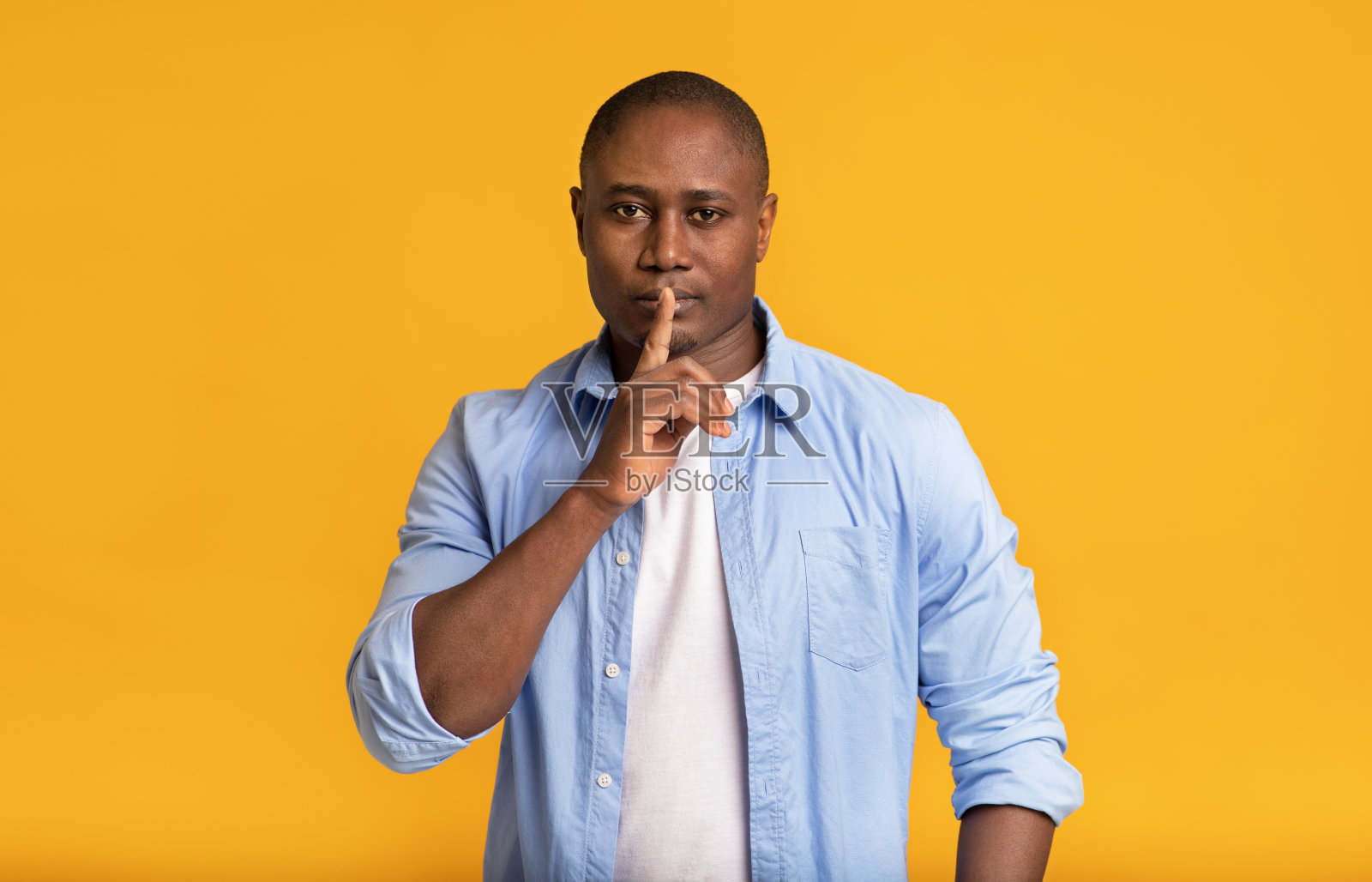 严肃自信神秘的成年非裔美国男性把手指放在嘴唇上表示沉默照片摄影图片