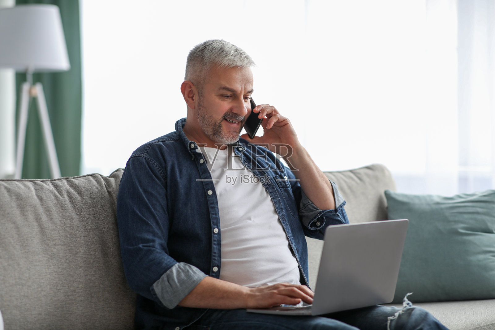 成熟的男人在网上工作，使用笔记本电脑和手机照片摄影图片
