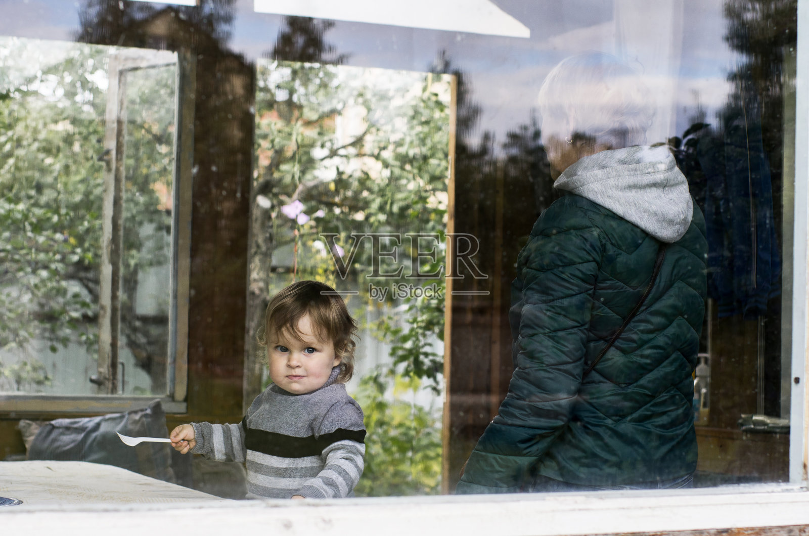 一个小女孩和她的奶奶在窗外的凉亭。家庭工作在花园里。家庭度假。祖母和孙女照片摄影图片