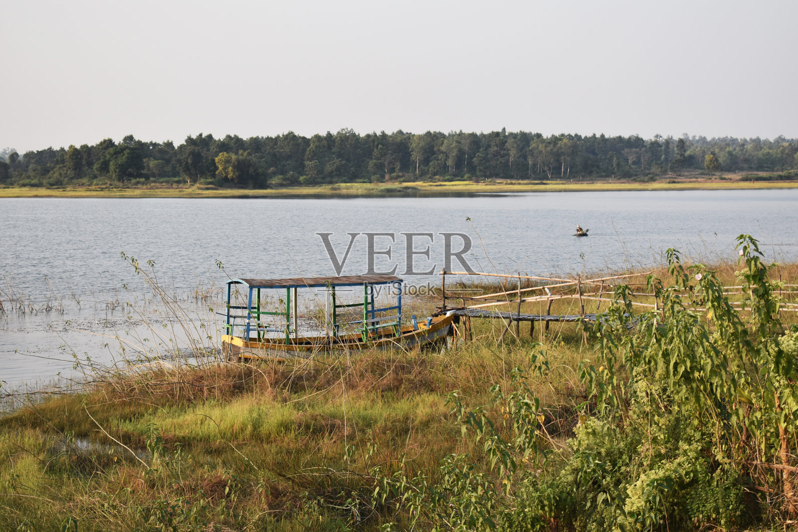 一只小船站在碧水绿野的湖边。照片摄影图片
