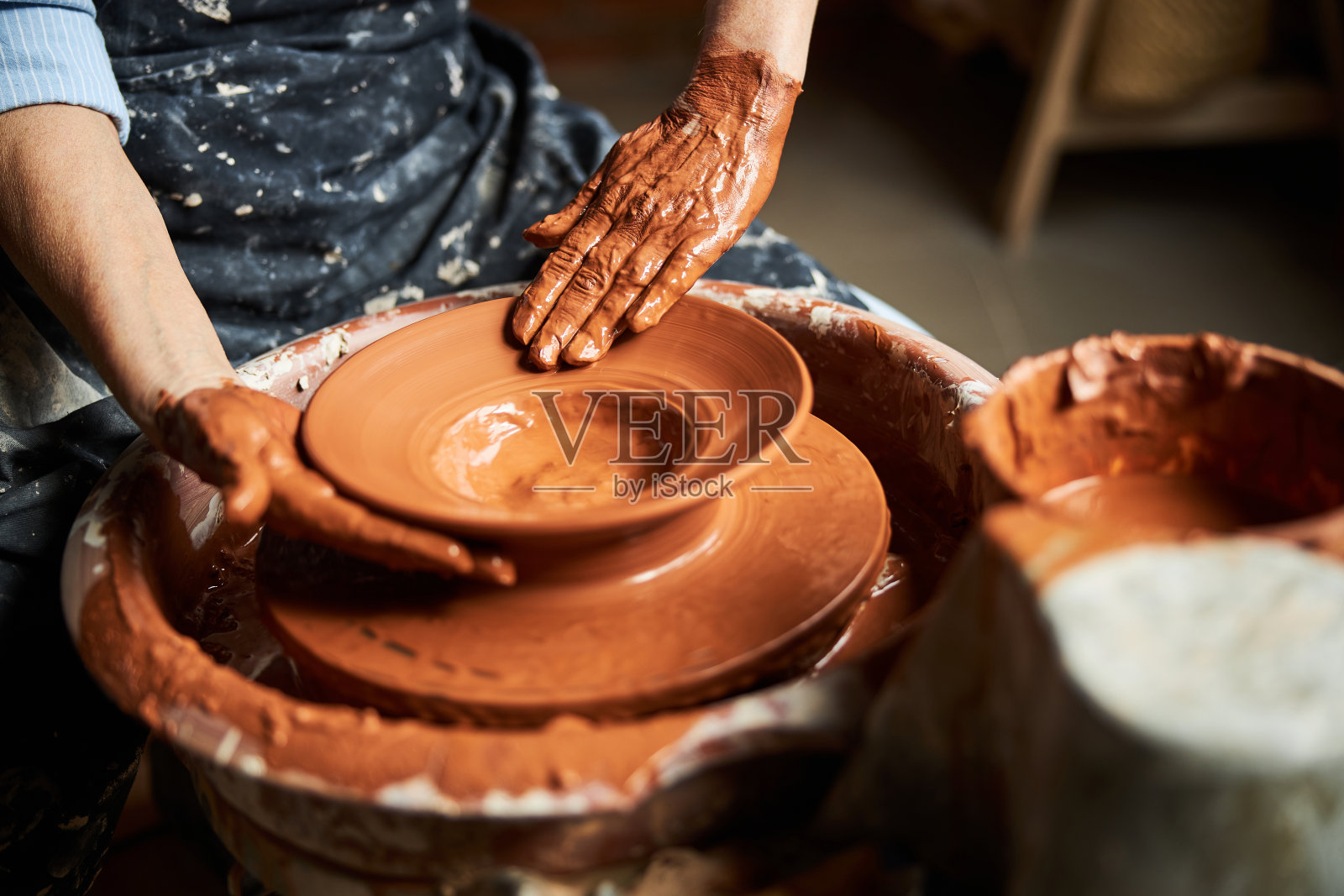 在陶艺作坊里，老婆婆在手工制作陶罐照片摄影图片