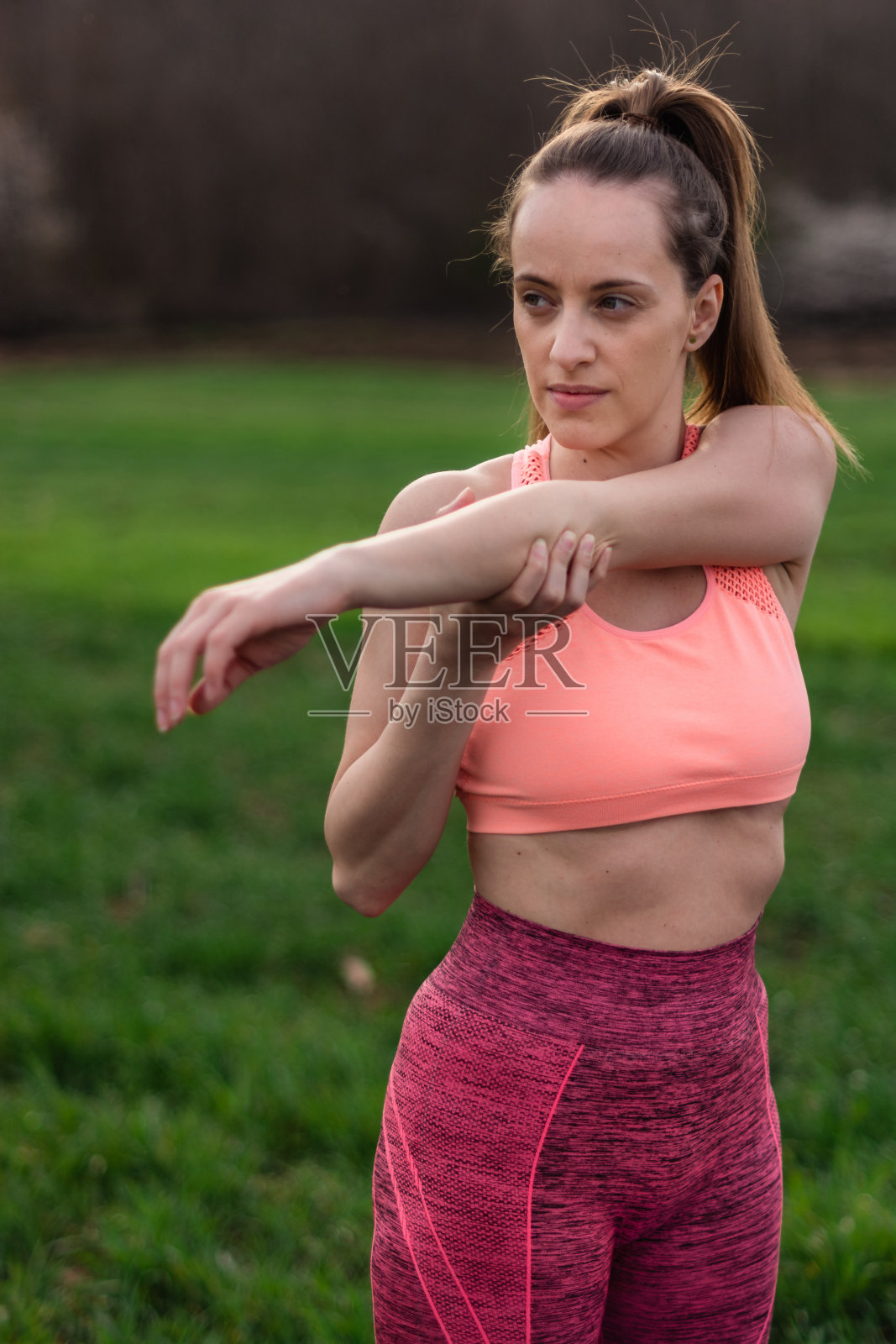 运动女性在公园里伸展她的手臂照片摄影图片