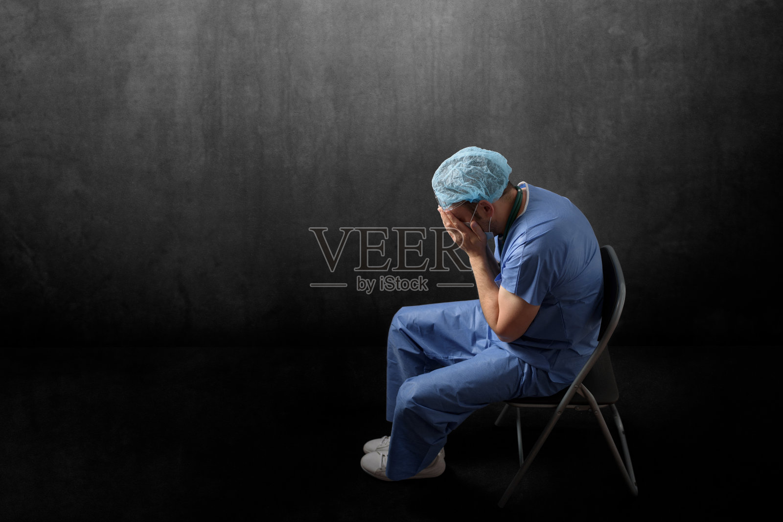 悲伤，疲惫的医生坐在黑暗的房间里照片摄影图片