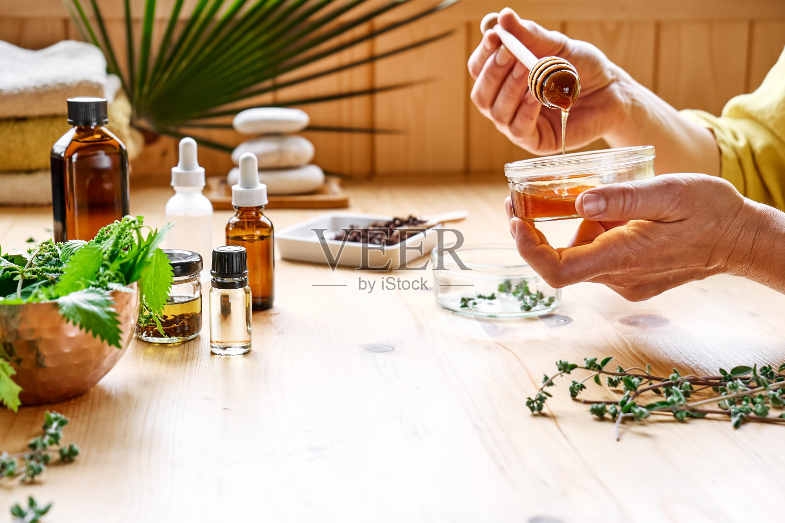 妇女在餐桌上准备香薰与精油扩散草药，不同类型的油和精华。芳香疗法和替代医学概念。自然的补救措施。照片摄影图片