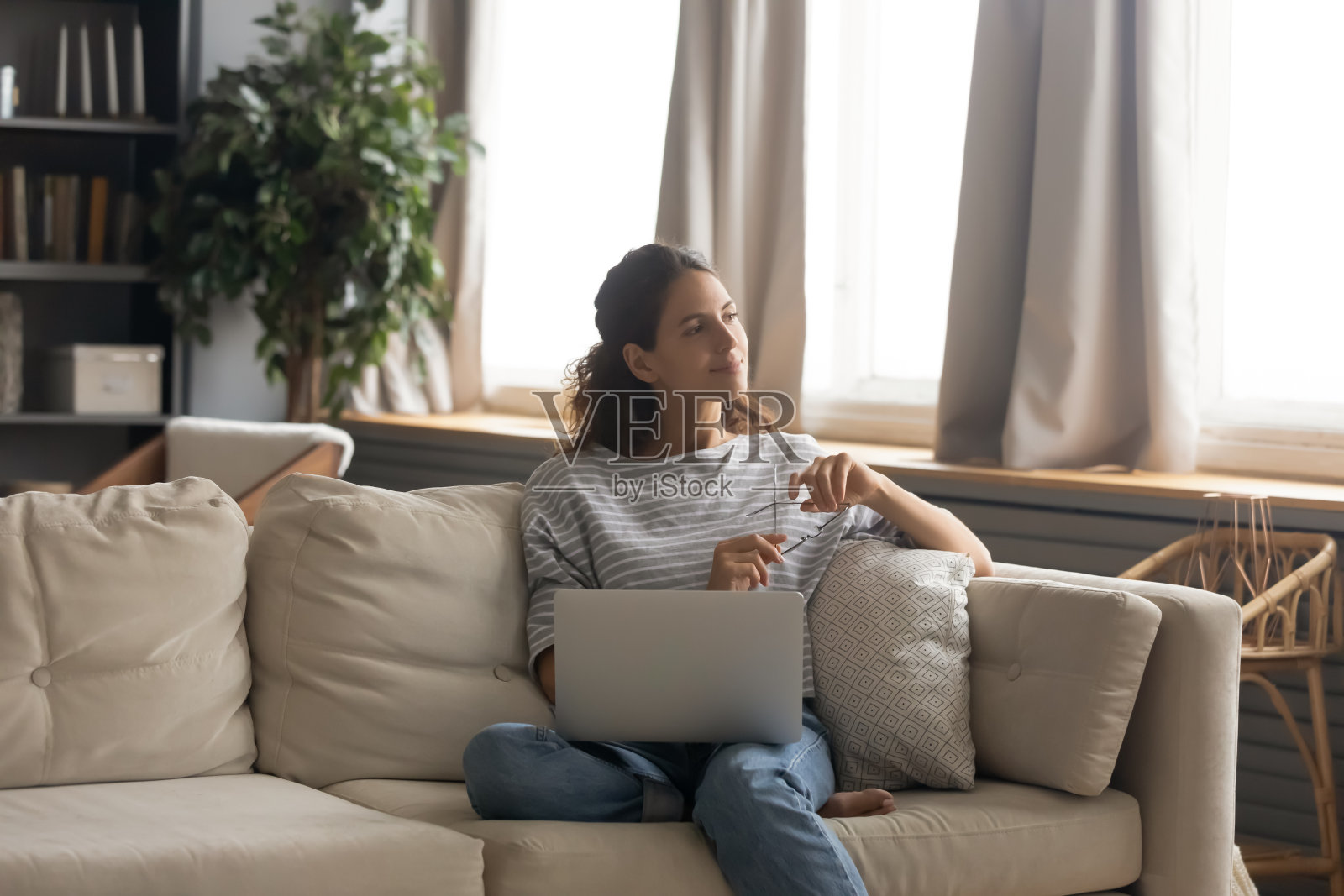 快乐的女人放松在沙发上用笔记本电脑做梦照片摄影图片