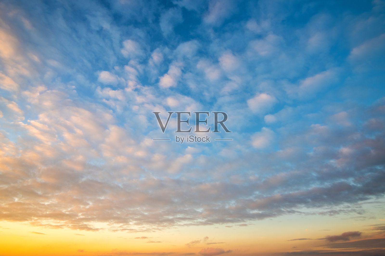 戏剧性的日落景观与蓬松的云被橙色的夕阳和蓝色的天空照亮。照片摄影图片