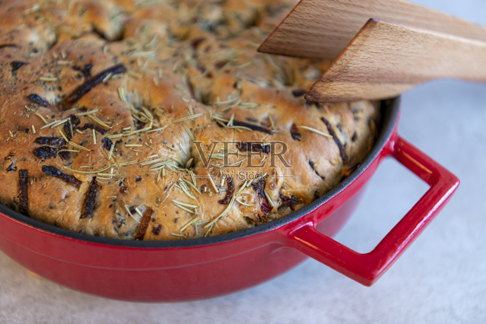 刚出炉的佛卡夏深盘面包在一个大的红色铸铁煎锅中烘烤。照片摄影图片