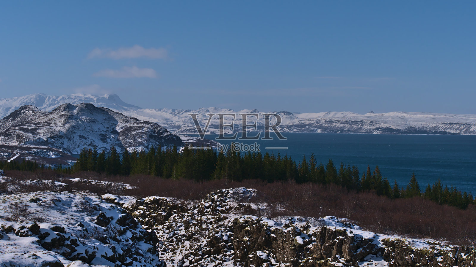 美丽的蓝色湖泊Þingvallavatn，冰岛最大的自然湖，在著名的Þingvellir国家公园，崎岖的，白雪覆盖的山脉和森林。照片摄影图片