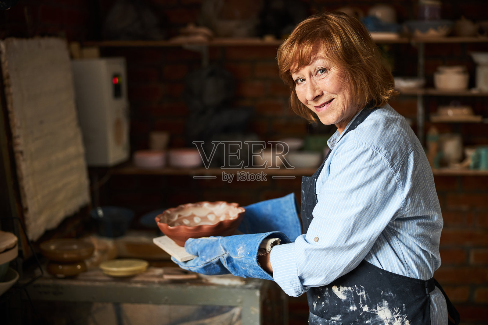 在陶艺工作室工作的快乐的高级女性照片摄影图片