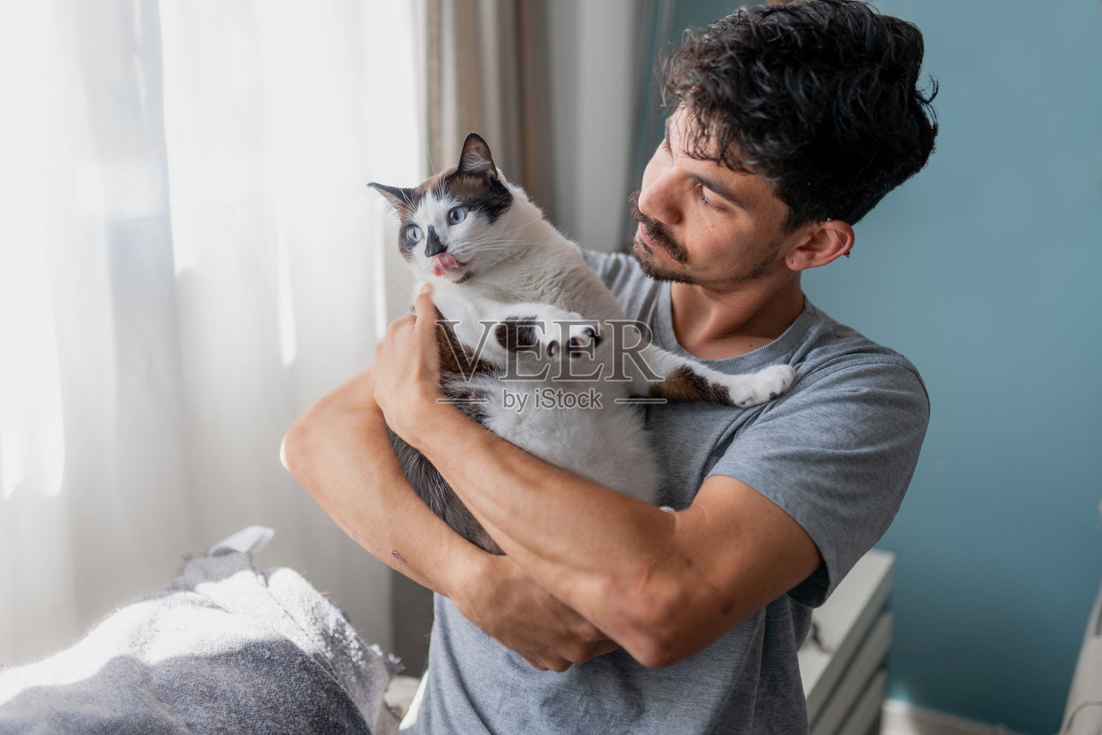 年轻人抱着一只蓝眼睛黑白相间的猫照片摄影图片