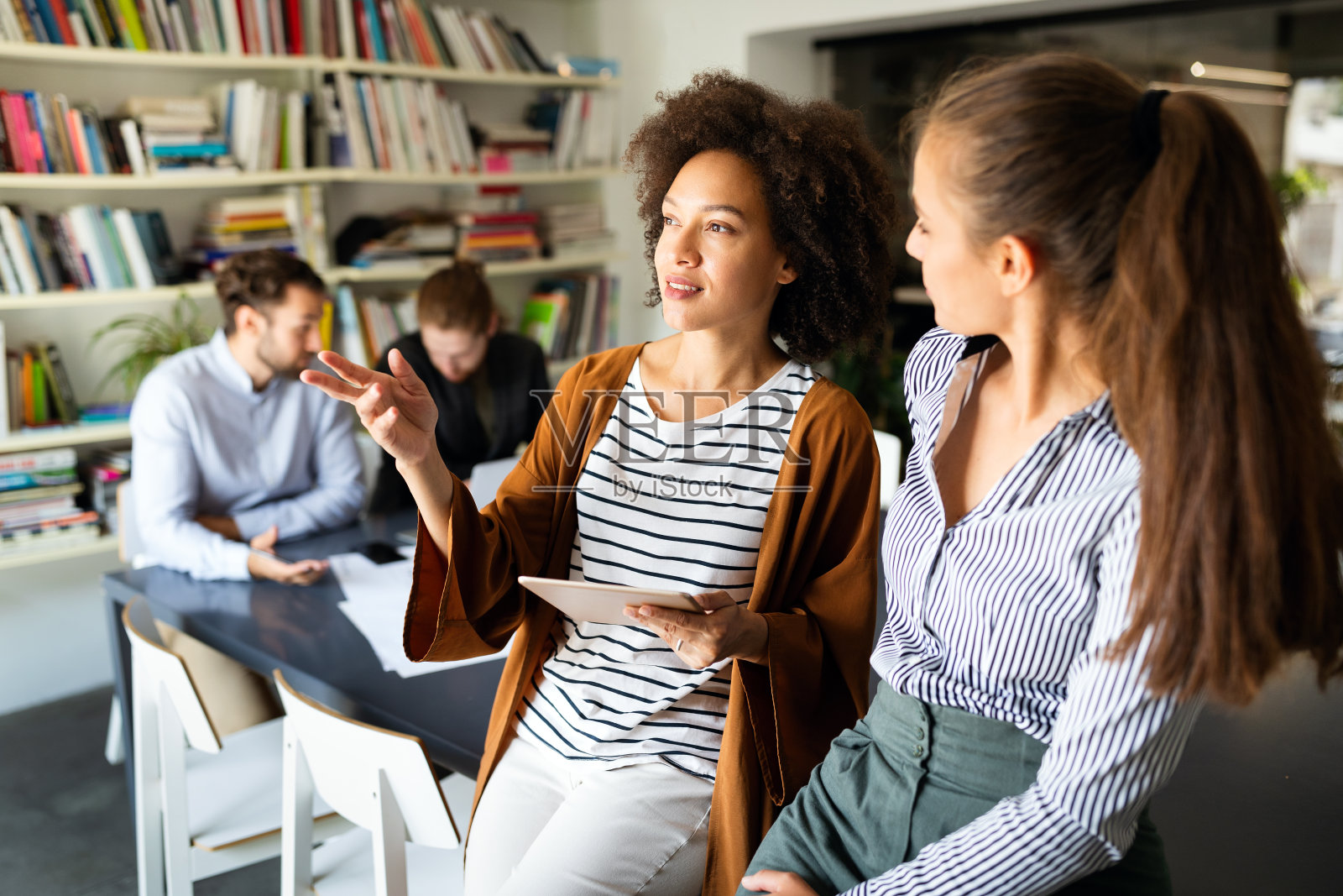 快乐的年轻商业人士同事在办公室谈论工作照片摄影图片