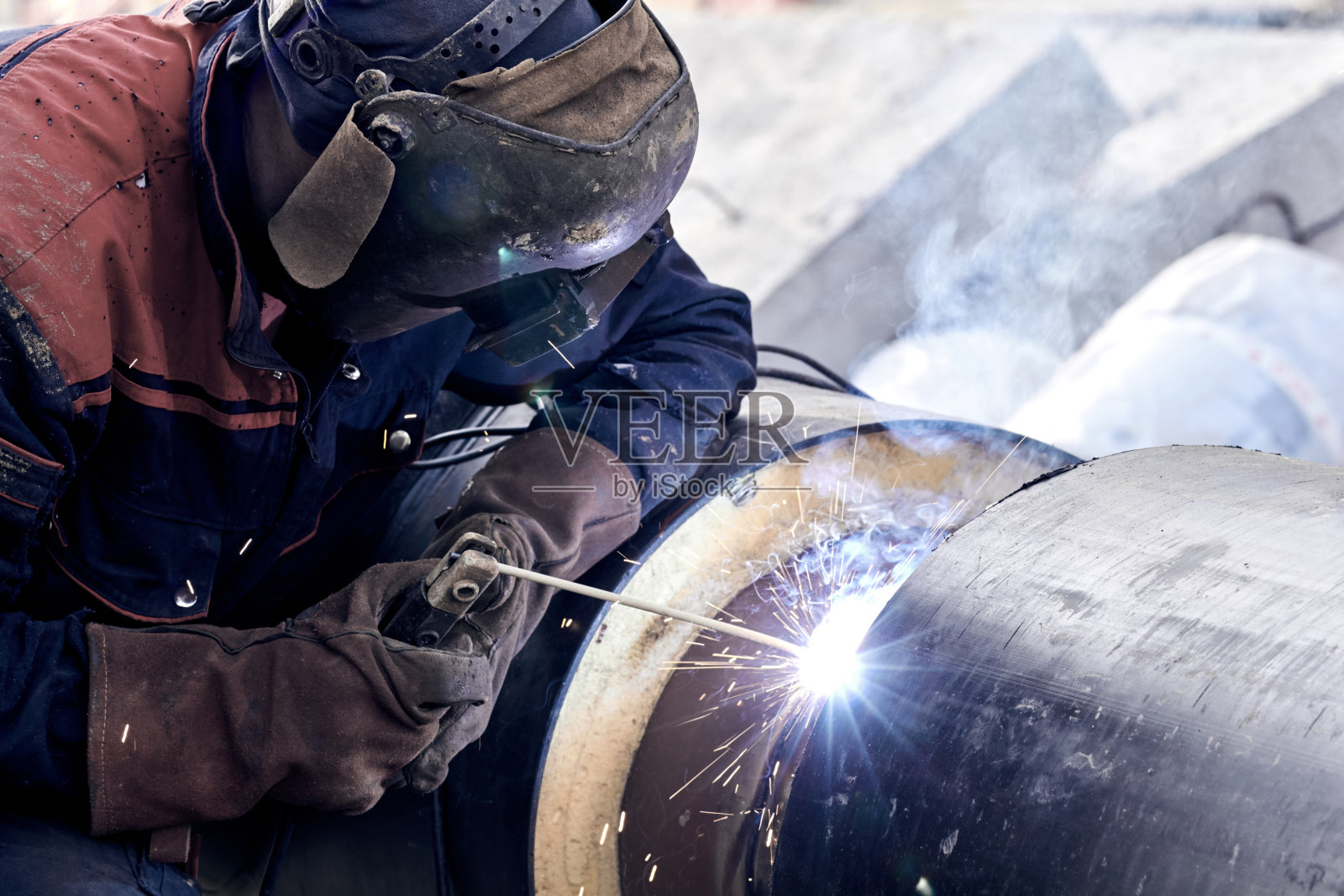 建筑工人正在用电弧焊接金属管。照片摄影图片