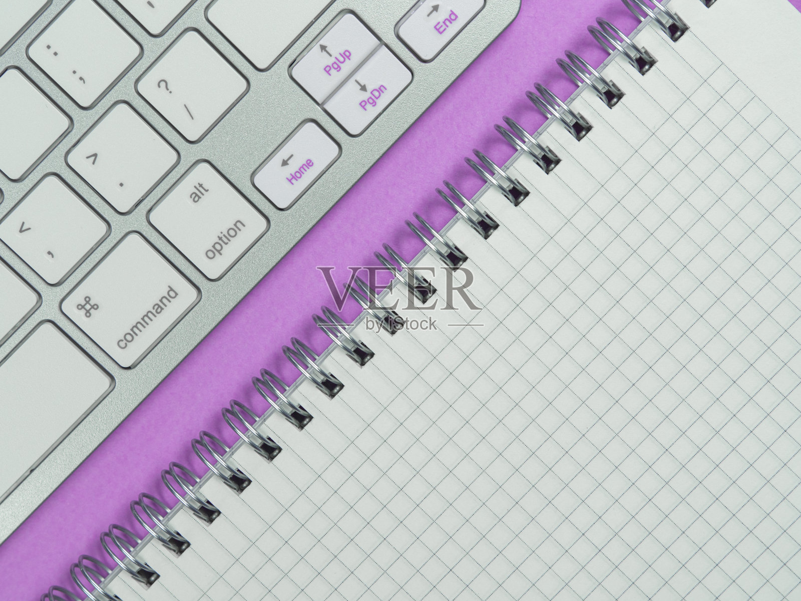 工作场所。粉红色背景上的办公室构思。键盘和记事本。平的。照片摄影图片