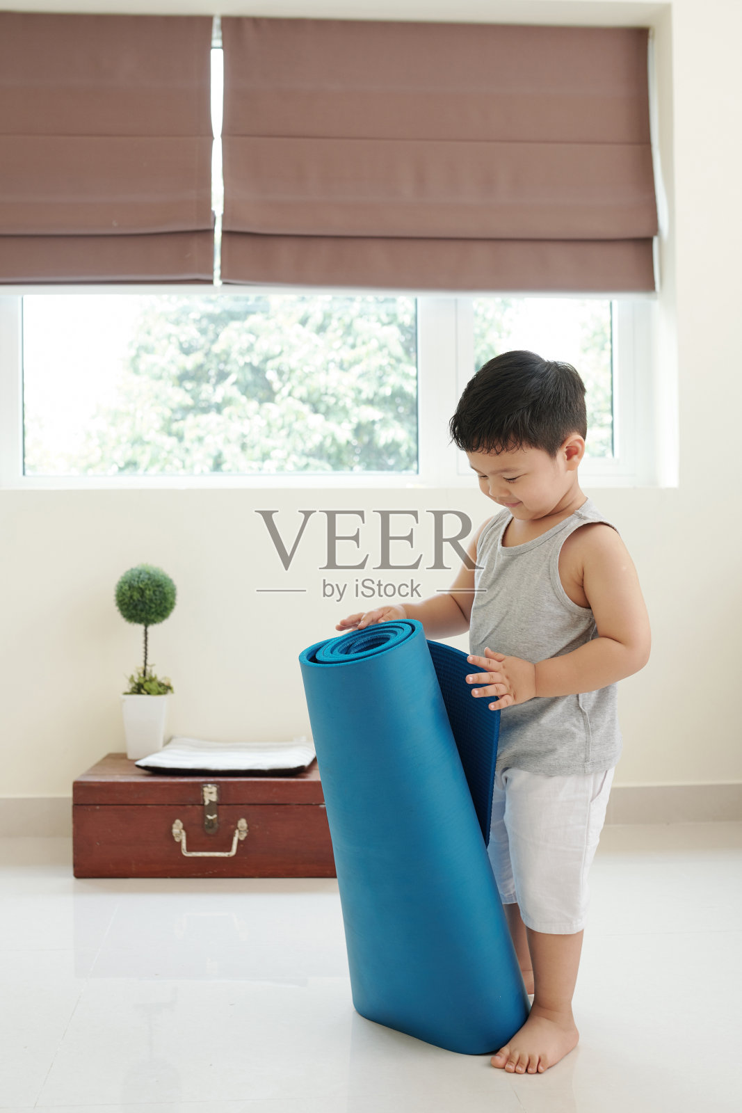 带着瑜伽垫的好奇男孩照片摄影图片