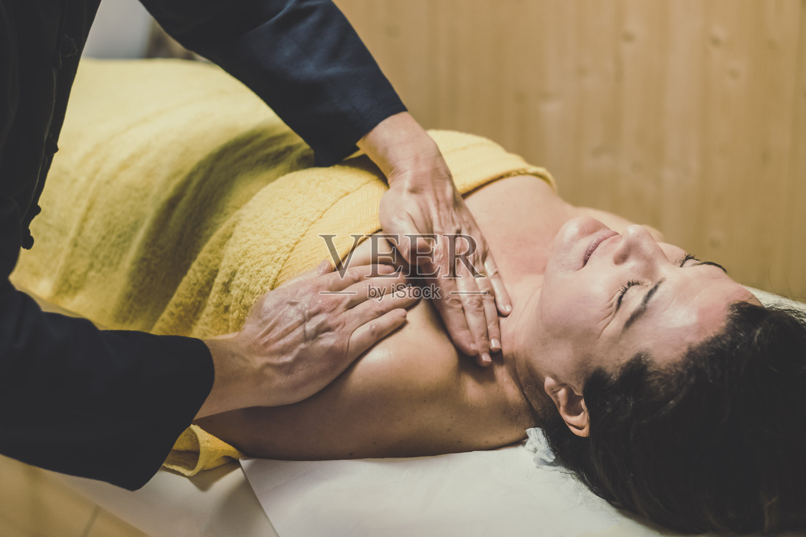 在一个健康中心，一个男人给一个女人按摩，抹了油的手在身体上放松肌肉，缓解紧张。健康幸福的概念照片摄影图片