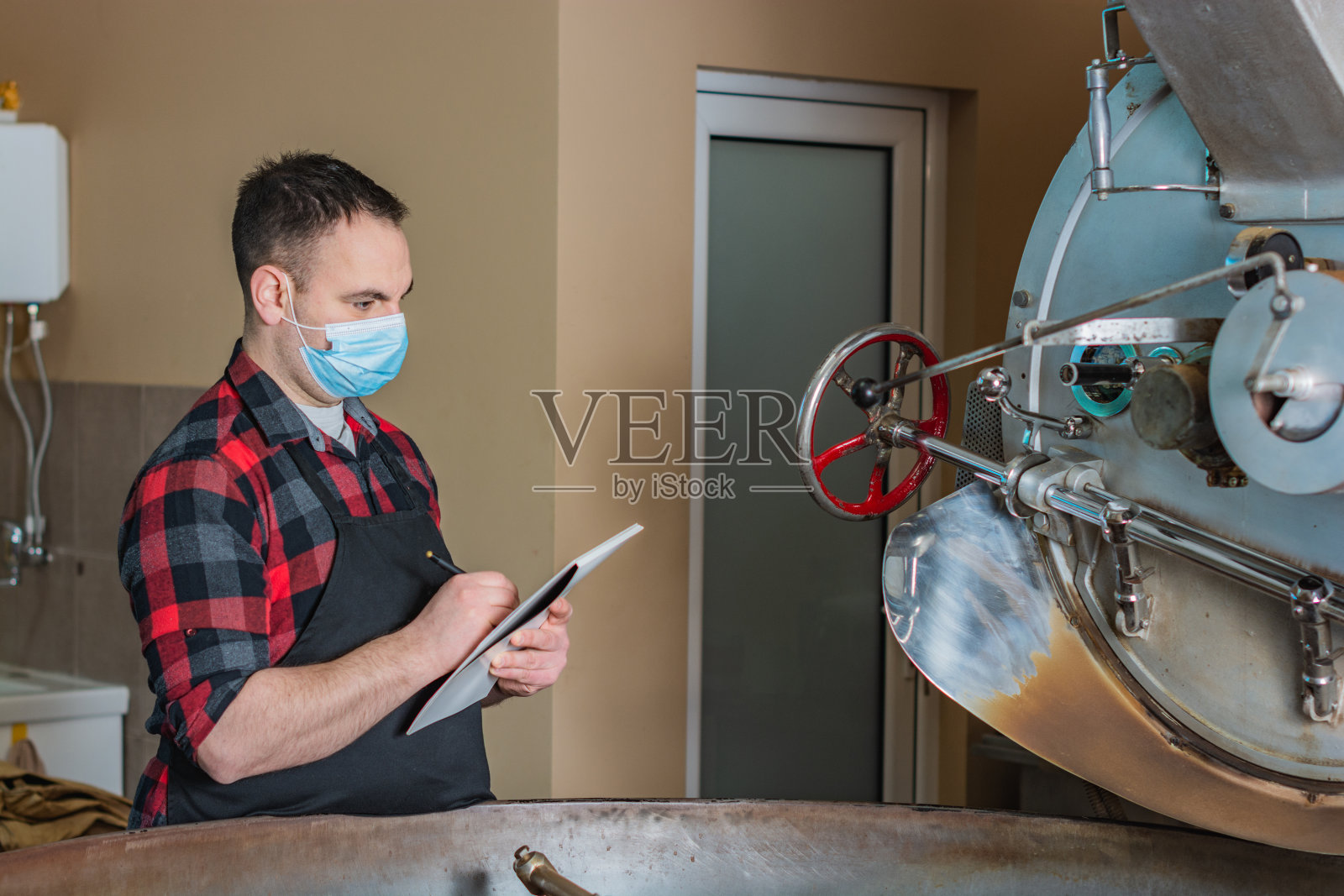 一名戴着口罩的严肃工人在一家咖啡店的烘焙工坊工作照片摄影图片