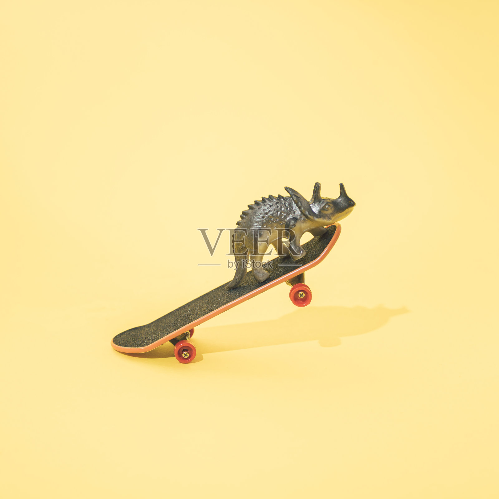 三角龙在滑板上。最小的设计。黄色背景。照片摄影图片