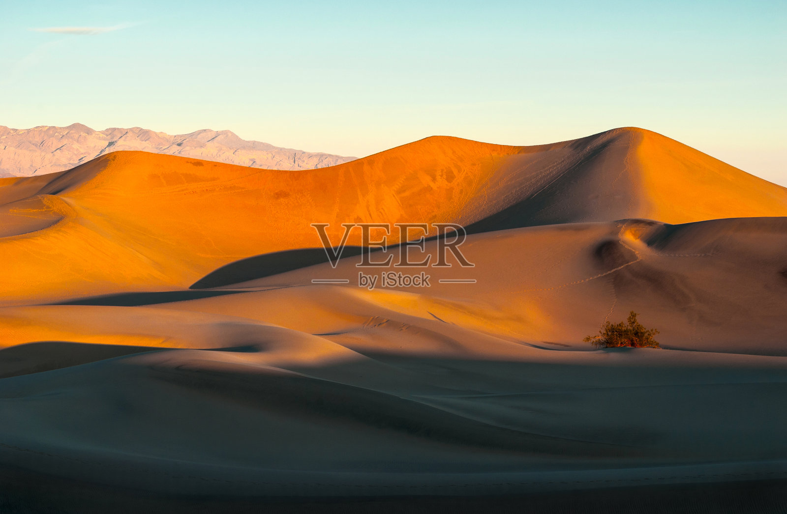 日出时，沙丘映衬着蓝天。照片摄影图片