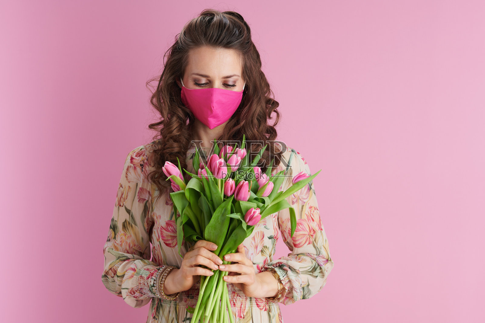 年轻的女子，有着浅黑色的长卷发和粉红色的头发照片摄影图片