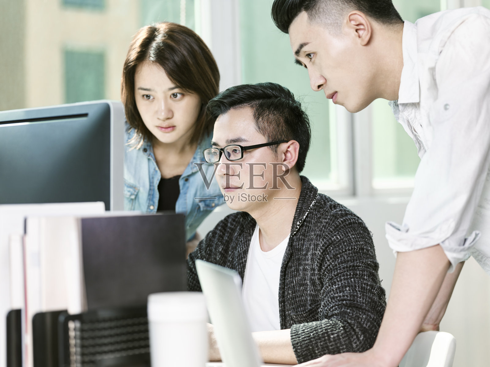 由三位年轻的亚洲企业家组成的团队正在办公室讨论业务照片摄影图片