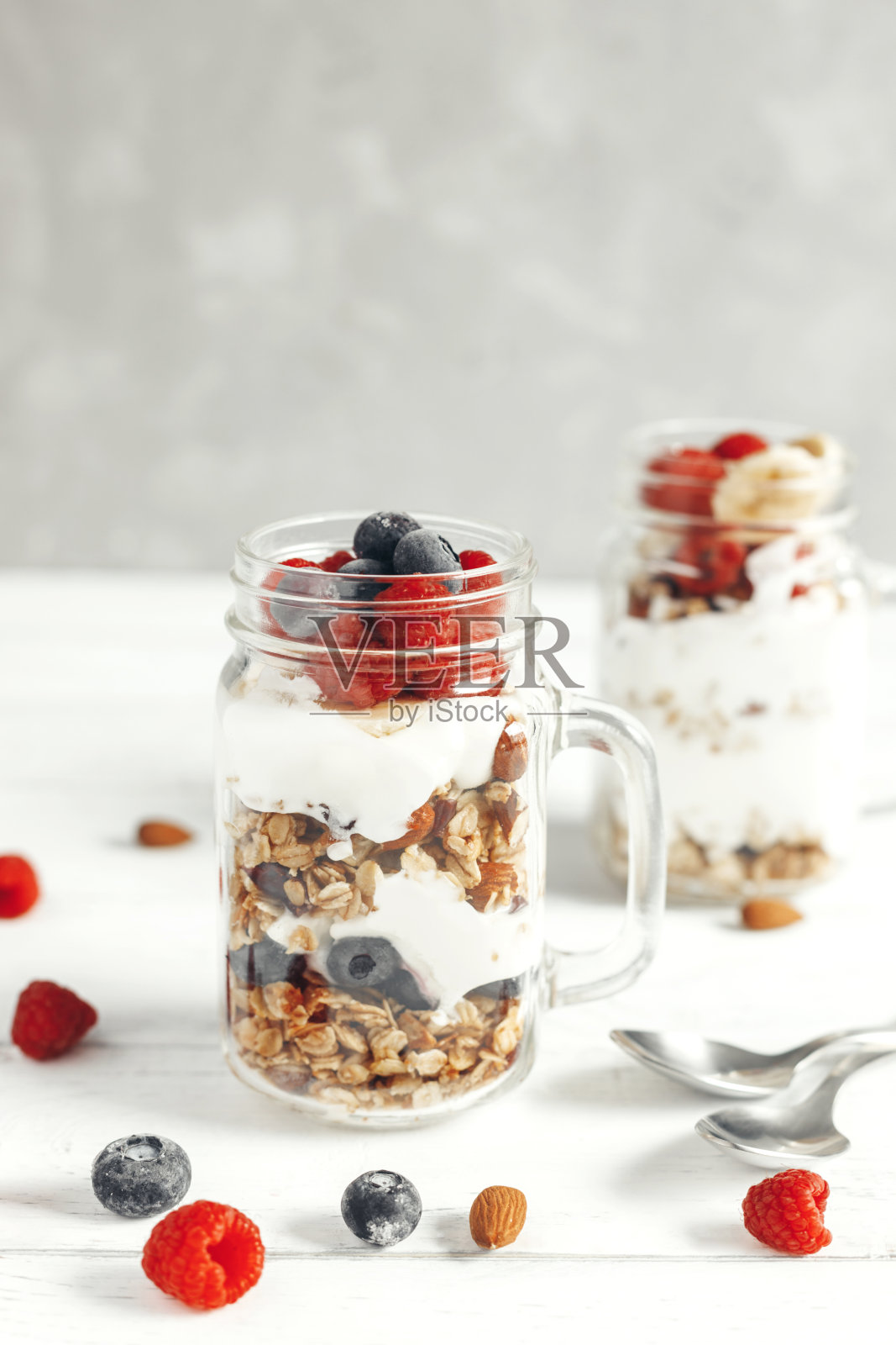 健康的早餐。燕麦麦片，酸奶和新鲜浆果装在玻璃罐里放在木板上。垂直的照片。文本的地方照片摄影图片