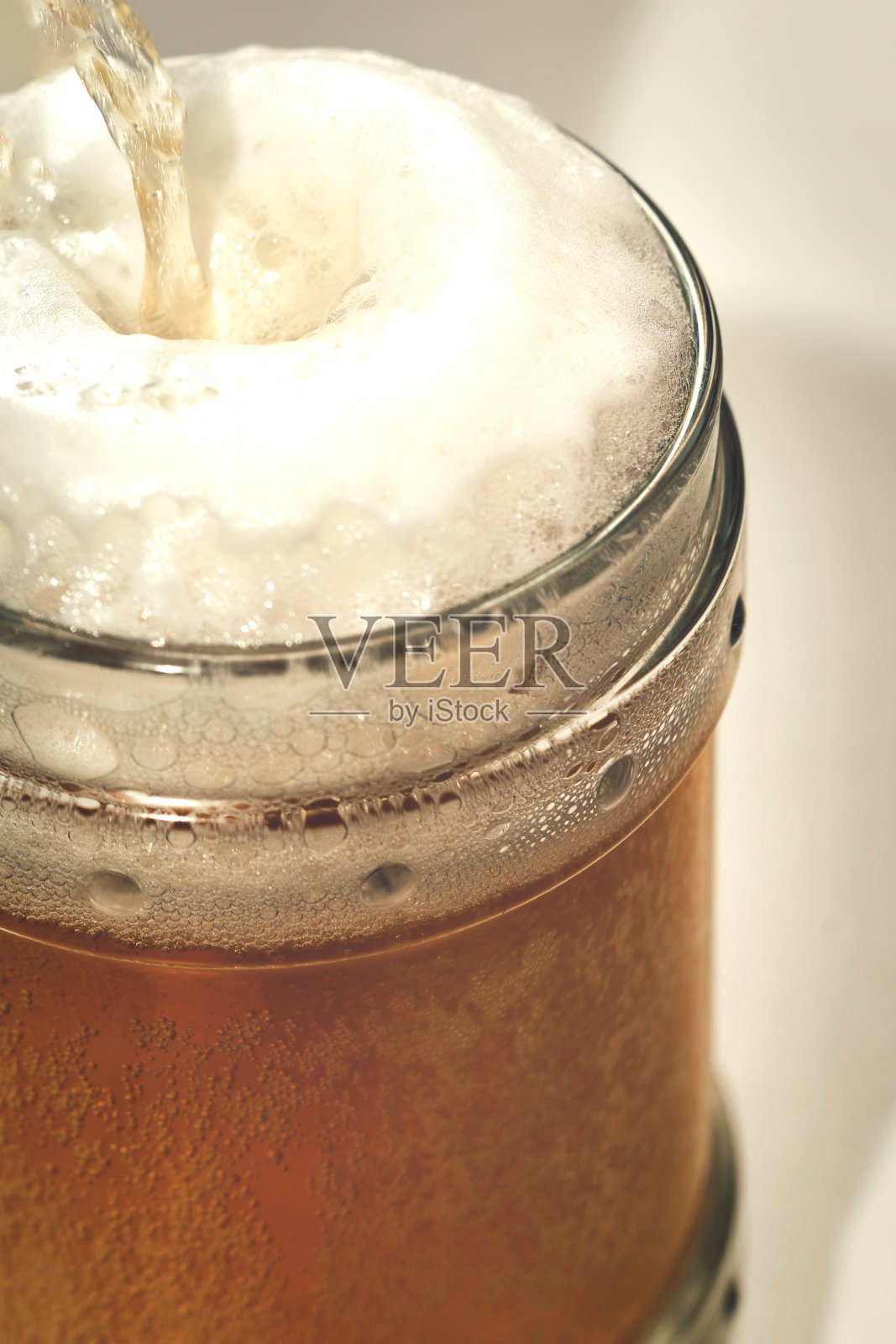 透明玻璃杯，上面有淡啤酒和泡沫。垂直拍摄照片摄影图片