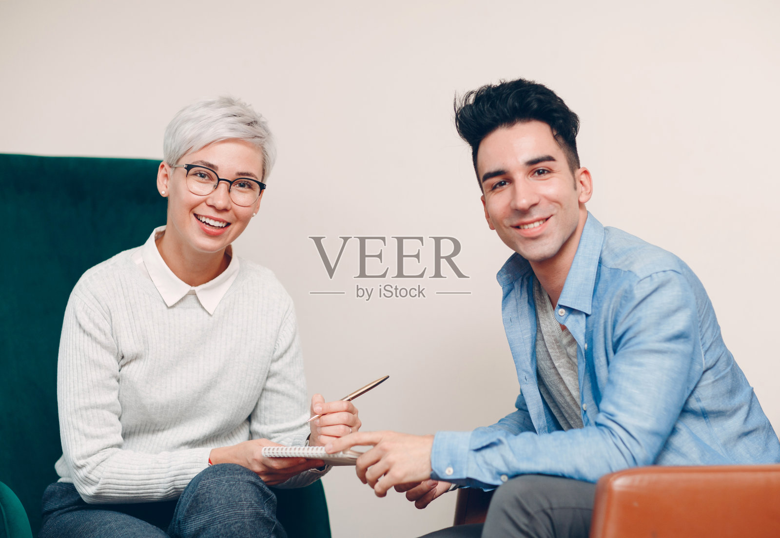 女人拿着笔和笔记本在写字，男人坐在一起的椅子上。新闻、面试和人力资源招聘调查合同的概念照片摄影图片