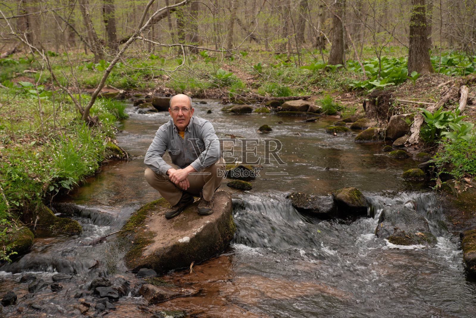 活跃的老年远足者在流动的小溪中踏石头照片摄影图片