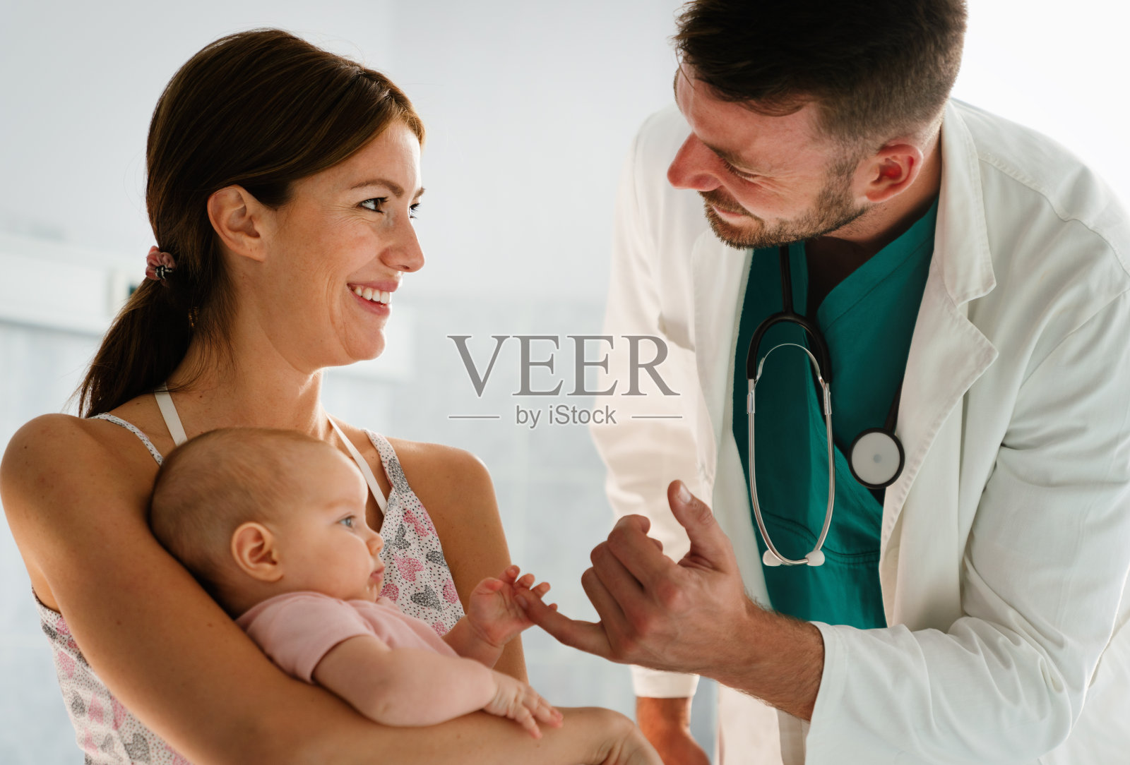 母亲抱着婴儿等待儿科医生检查照片摄影图片