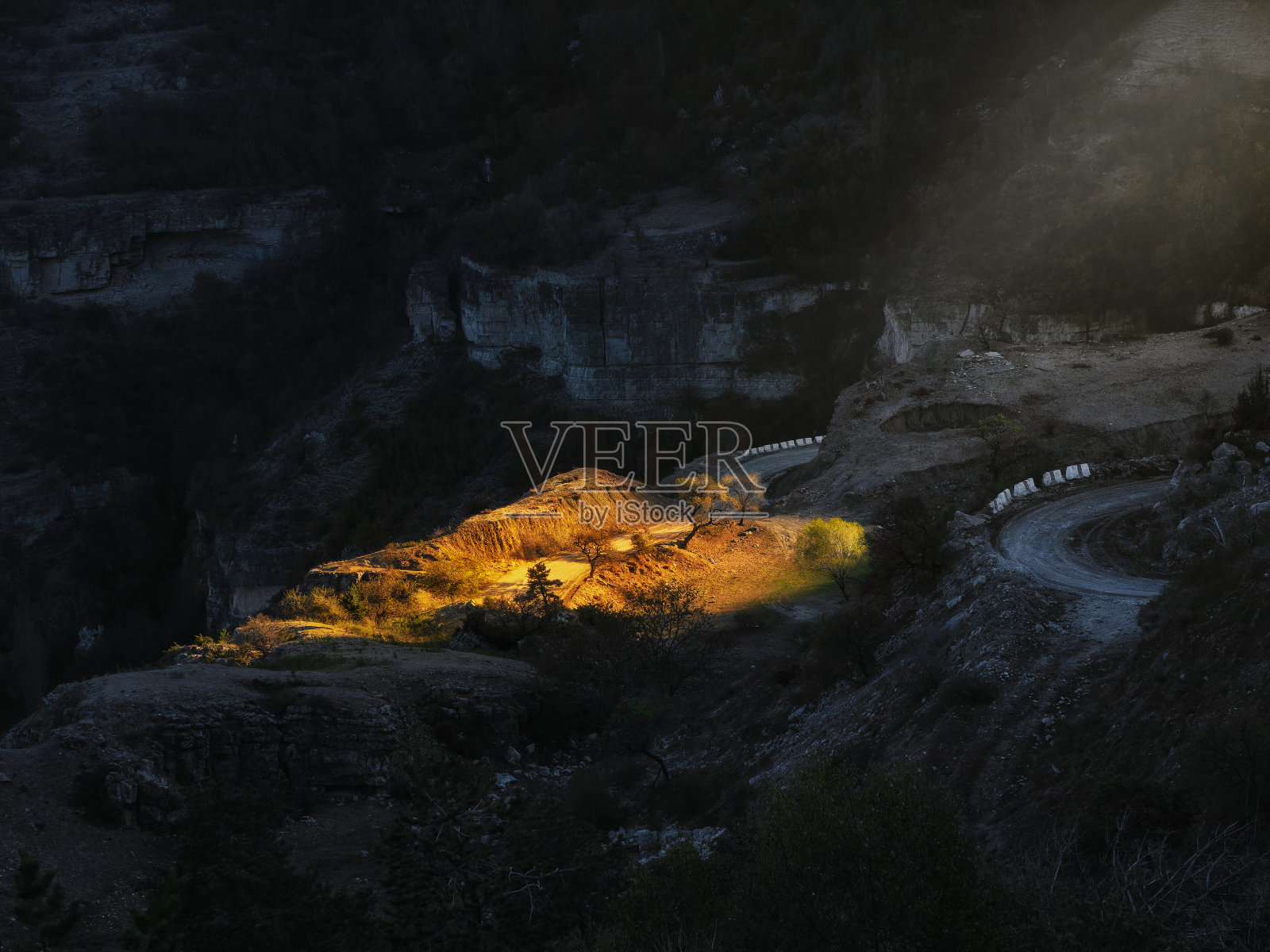 清晨的阳光，照耀着群山，蜿蜒的道路从山上向下延伸照片摄影图片