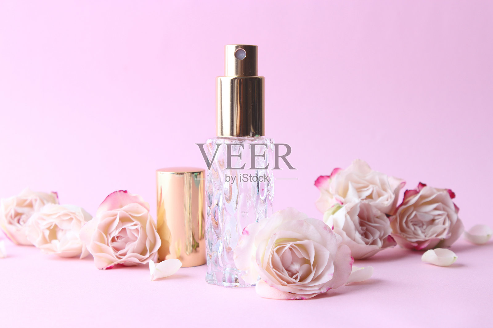 香水瓶和玫瑰花在一个光背景近距离照片摄影图片
