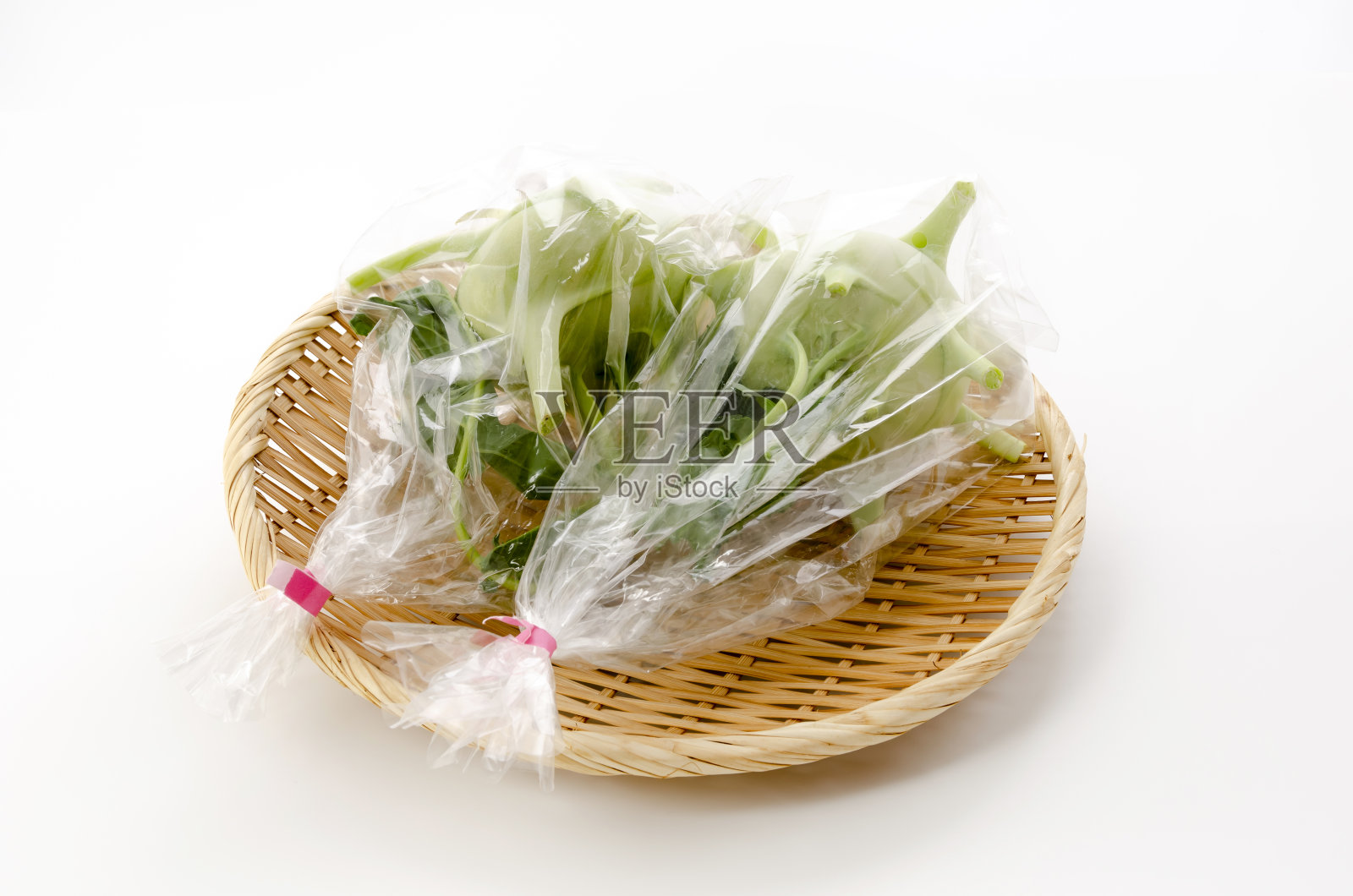 袋装新鲜大头菜，竹筛上白底照片摄影图片