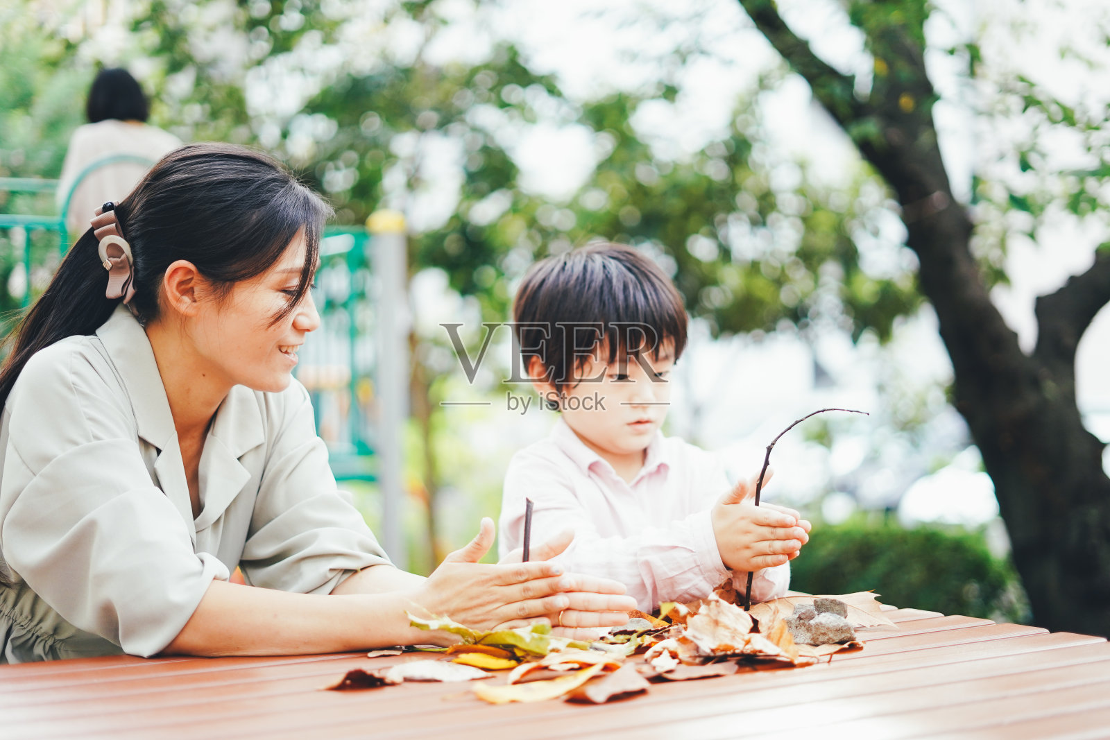 妈妈和儿子在玩树叶照片摄影图片