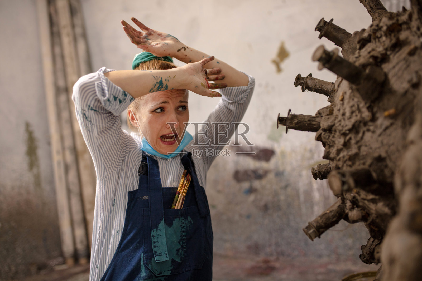 女艺术家在车间里与一个冠状病毒雕塑。照片摄影图片