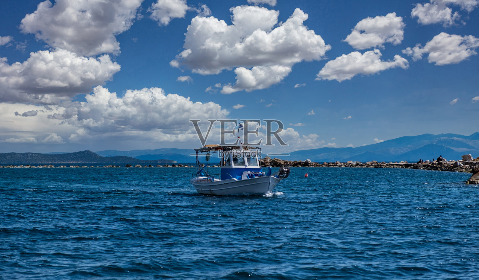 渔船在波涛汹涌的海面上航行，阴云密布的蓝天为背景。照片摄影图片