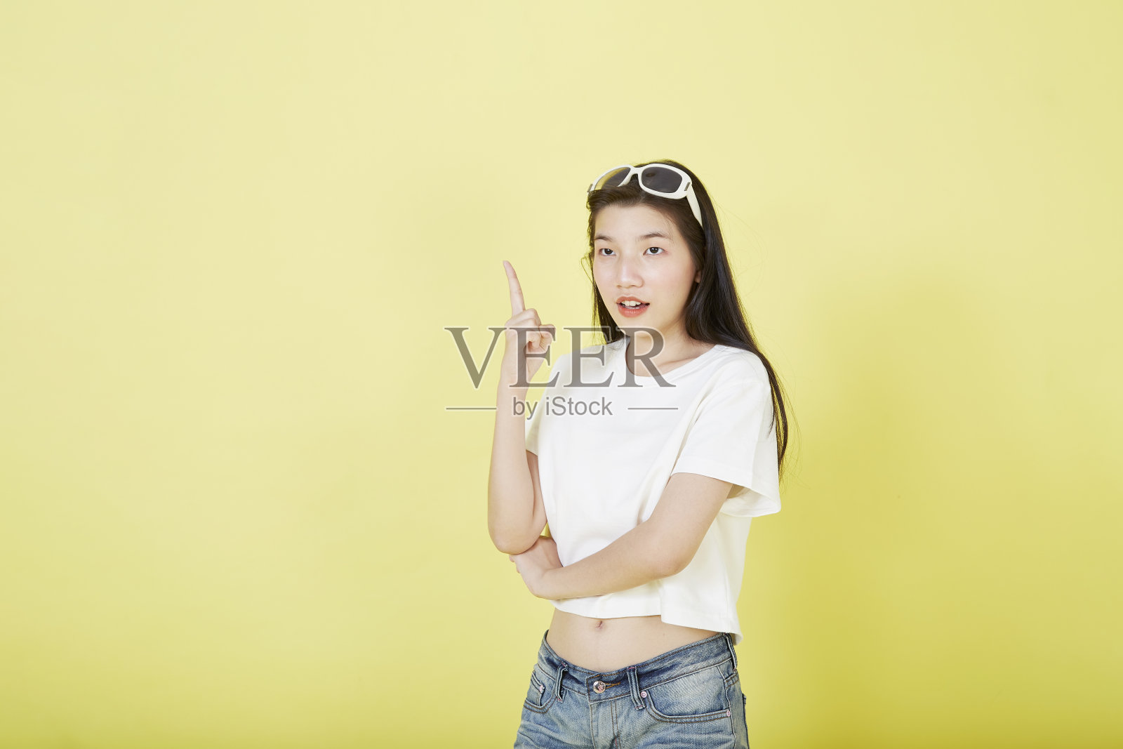 年轻优雅美丽的亚洲女人微笑着指着空荡荡的复印空间孤立的黄色背景照片摄影图片