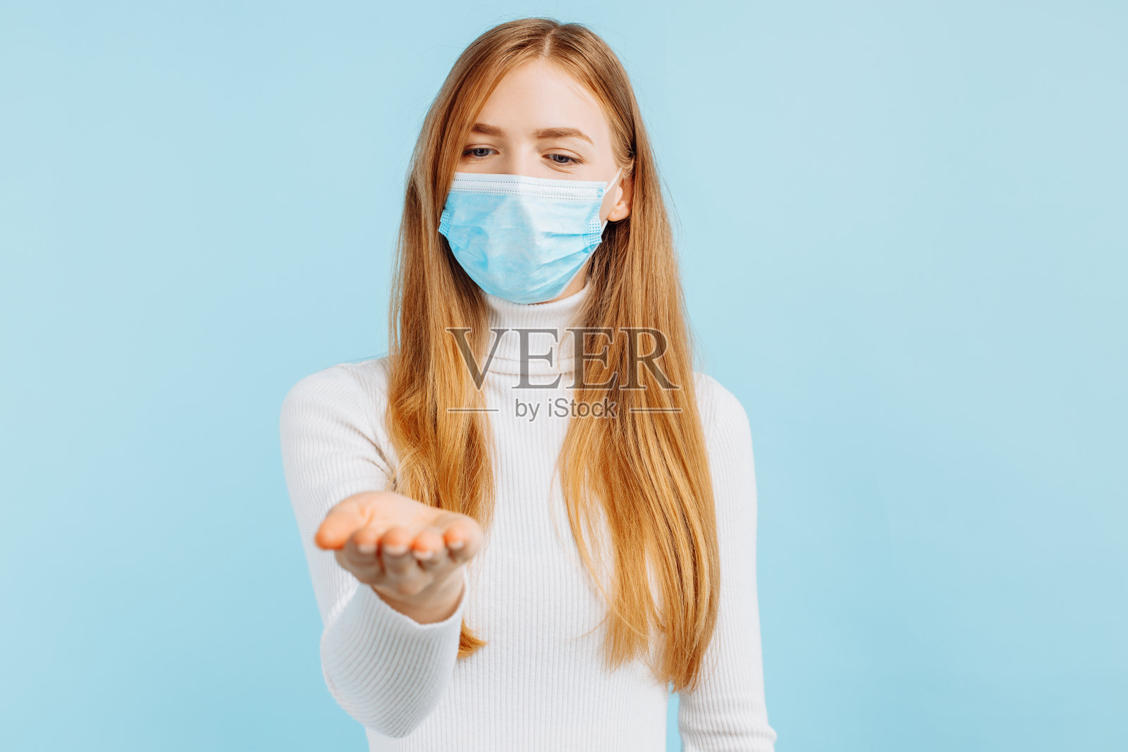 年轻女子在医疗面罩指向手指复制空间隔离在蓝色背景照片摄影图片