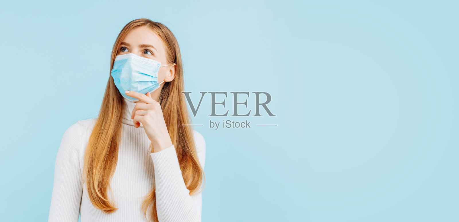 神奇的女人戴着医用面具仰望着空旷的空间，沉思的男人，在蓝色的背景下照片摄影图片