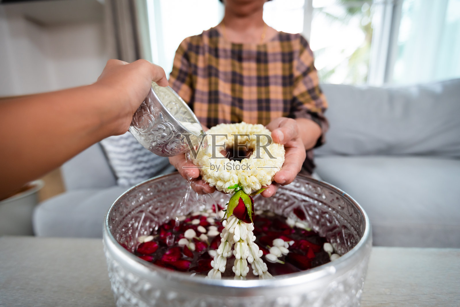 在新年泼水节，孩子把水倒在年长的长辈或尊敬的祖父母手上，他们手持茉莉花花环庆祝泼水节。照片摄影图片