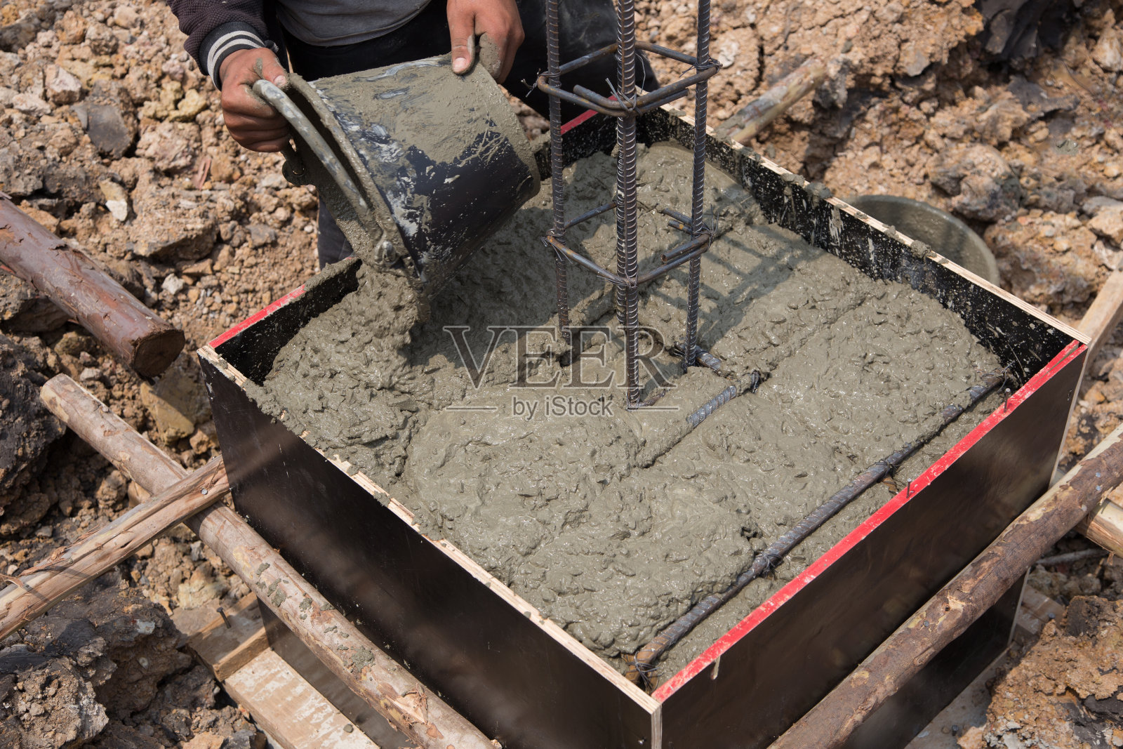 新楼的建筑工地。用人力把混凝土拉到框架上照片摄影图片